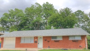 A single-story brick house with a garage, a front door, and a small porch area. - Cozy Retreat with a Fenced Yard (Huber Heights)