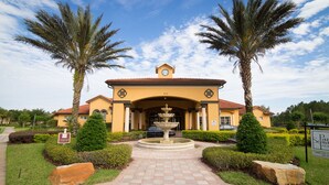 A hotel entrance with a fountain, palm trees, and a clear sky. - Pool Home With Spa & Games Room In Gated Resort With Extensive Amenities (Davenport)
