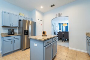 A modern kitchen with light blue cabinets, a stainless steel refrigerator, and a granite countertop. - Highlands Reserve Pool Home With Spa Close to WDW (202CPD) (Davenport)