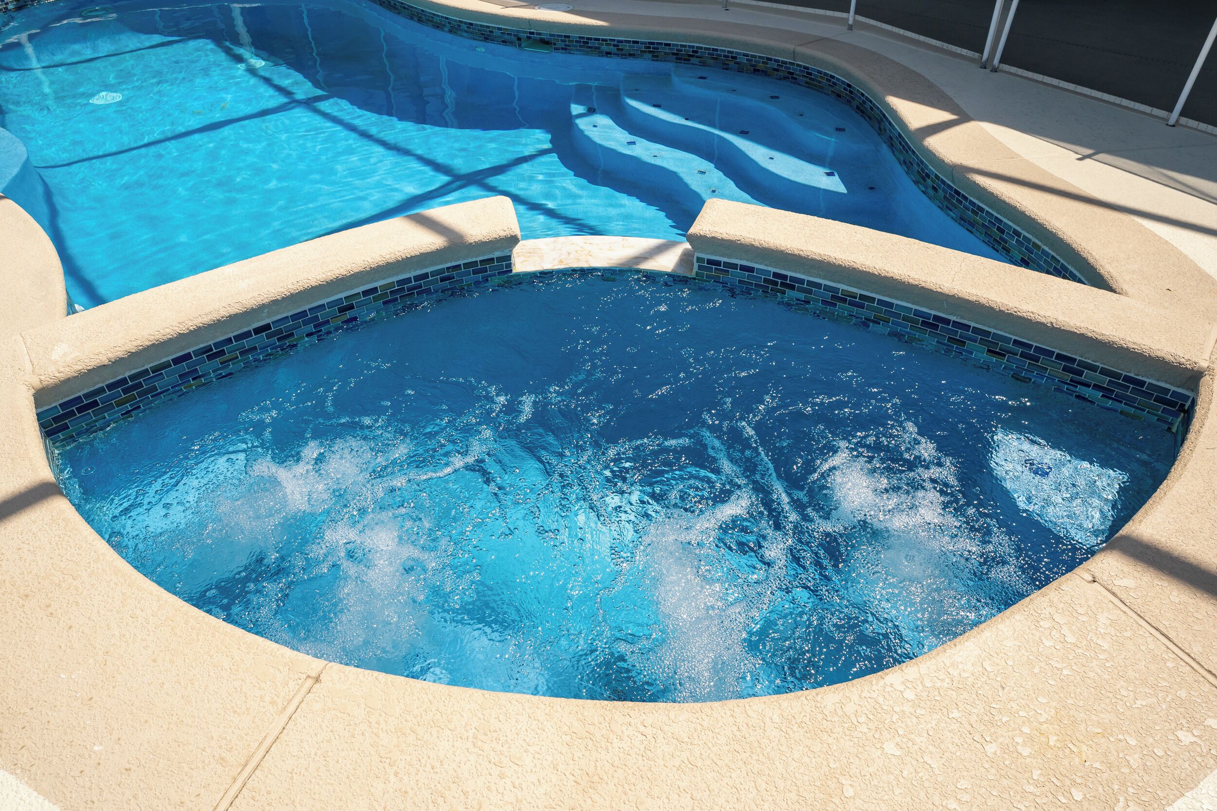 Une piscine dont le bord est revêtu de carreaux et dont la forme est incurvée.