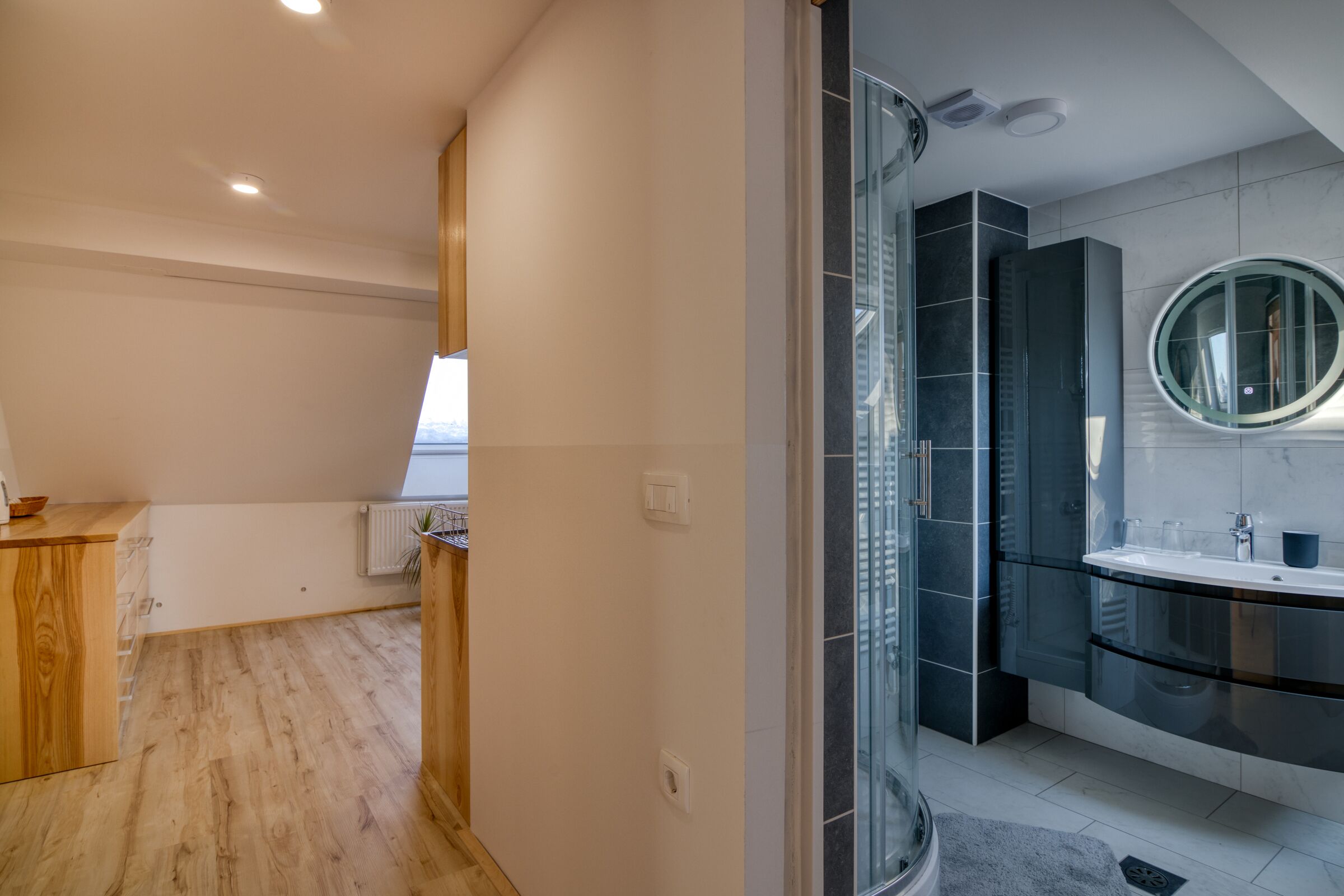 A modern bathroom with a glass shower enclosure, a curved vanity, and a large mirror.