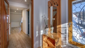 A hallway with wooden flooring, a mirror with a wooden frame, and a door with a glass window.