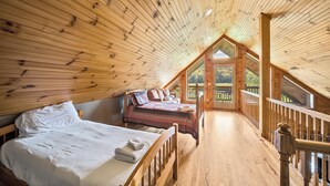A wooden ceiling with a sloped design, a bed with a white comforter, and a wooden railing on a balcony. - Cruizin River Dreams- Riverfront, fire pit, hot tub (Todd)