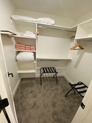 A walk-in closet with shelves, a bench, and hanging space.