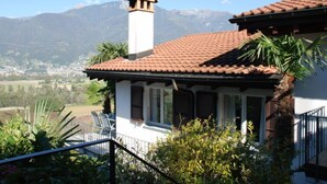 Une maison avec un toit en tuiles, une cheminée et une vue sur les montagnes.
