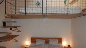 Une chambre avec un lit superposé, des étagères en bois, des lampes de chevet et un lit avec des oreillers et des vêtements pliés.