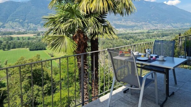 Une terrasse avec une table et des chaises donnant sur un paysage montagneux.