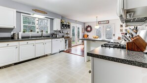 A spacious kitchen with white cabinets, a granite countertop, and a gas stove. - Sterling Valley Home ~ 9 Mi to Stowe Mountain! (Morristown)