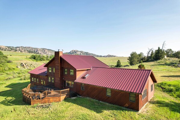 Una cabaña de madera con techo rojo, un porche y vistas del paisaje circundante.