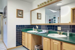 Un baño con dos lavamanos, armarios de madera, un espejo y un salpicadero de azulejos.