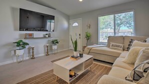 A living room with a sofa, a coffee table, and a TV mounted on the wall. - Desert Hot Springs Home w/ Pool & Gas Grill! (Desert Hot Springs)