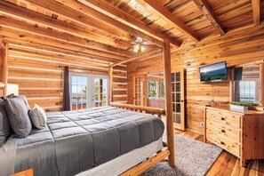 A wooden cabin bedroom with a bed, dresser, and TV.