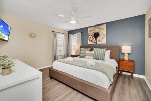 A neatly arranged bedroom with a bed, bedside table, and a ceiling fan.