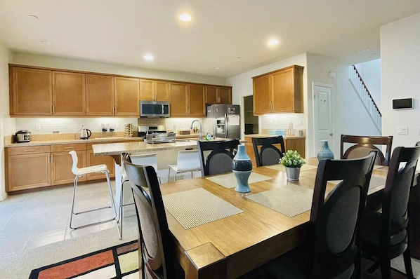 Una cocina moderna con armarios de madera, electrodomésticos de acero inoxidable y un comedor con mesa y sillas de madera.
