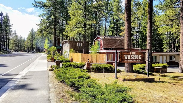 Eine Lodge namens 'The Washoe' mit einem rustikalen Holzschild, umgeben von dichten Kiefern.