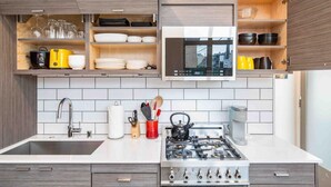 A modern kitchen with a gas stove, white tiles, and wooden cabinets. - Walkable in Heart of Ballard (Seattle)