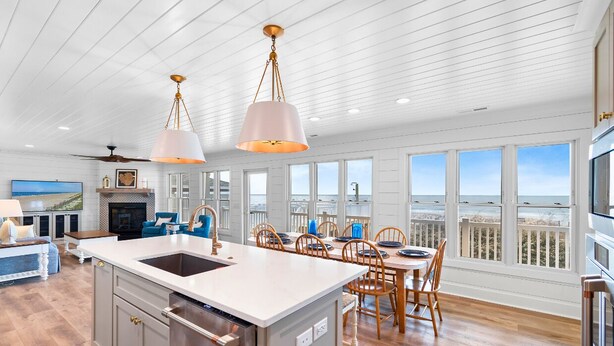 A spacious kitchen with a large island, wooden dining table, and chairs, overlooking a scenic view. - "Porpoise Point" - Oceanfront Home, 5 Bedrooms / 5 Bathrooms, w/ PRIVATE POOL (Holden Beach)