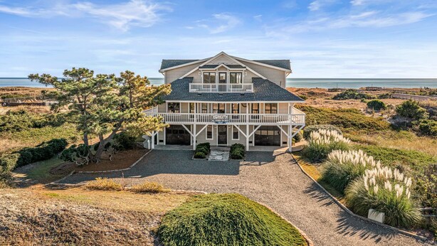 A two-story beachfront house with a balcony, surrounded by landscaped gardens and a view of the ocean. - "All Hands On Deck" Oceanfront with elevator 5 bedrooms, 5 bathrooms. (Holden Beach)