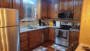 A kitchen with wooden cabinets, stainless steel appliances, a microwave, and a coffee maker.