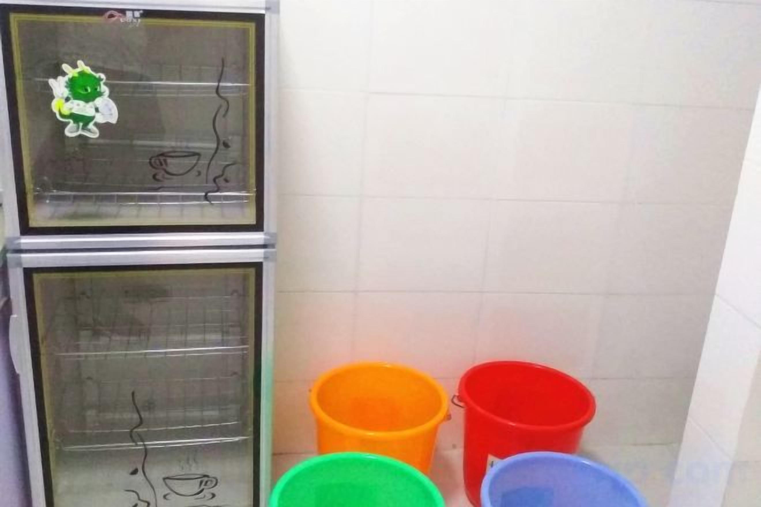 A kitchen with two ovens and three colorful buckets.