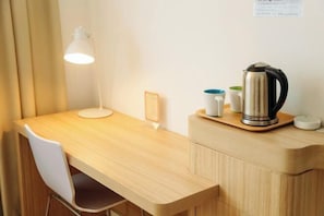 A wooden desk with a lamp, a kettle, and a cup on a tray. - Jiangcheng Hotel (Wuhu Fangte Phase 2 Ocean Park) (Wuhu)