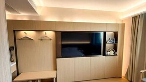 A modern hotel room with a bed, a TV, a seating area, and a small kitchenette. - Jiangcheng Hotel (Wuhu Fangte Phase 2 Ocean Park) (Wuhu)