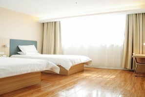 A hotel room with two beds, wooden flooring, a desk, and a large window with curtains. - Jiangcheng Hotel (Wuhu Fangte Phase 2 Ocean Park) (Wuhu)