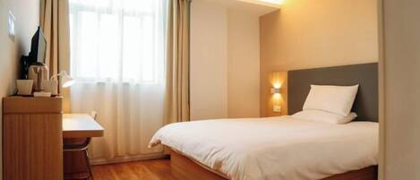 A hotel room with a bed, a desk, and a chair.