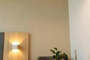 Et værelse med en træpanelvæg, en vægmonteret lampe og en potteplante.