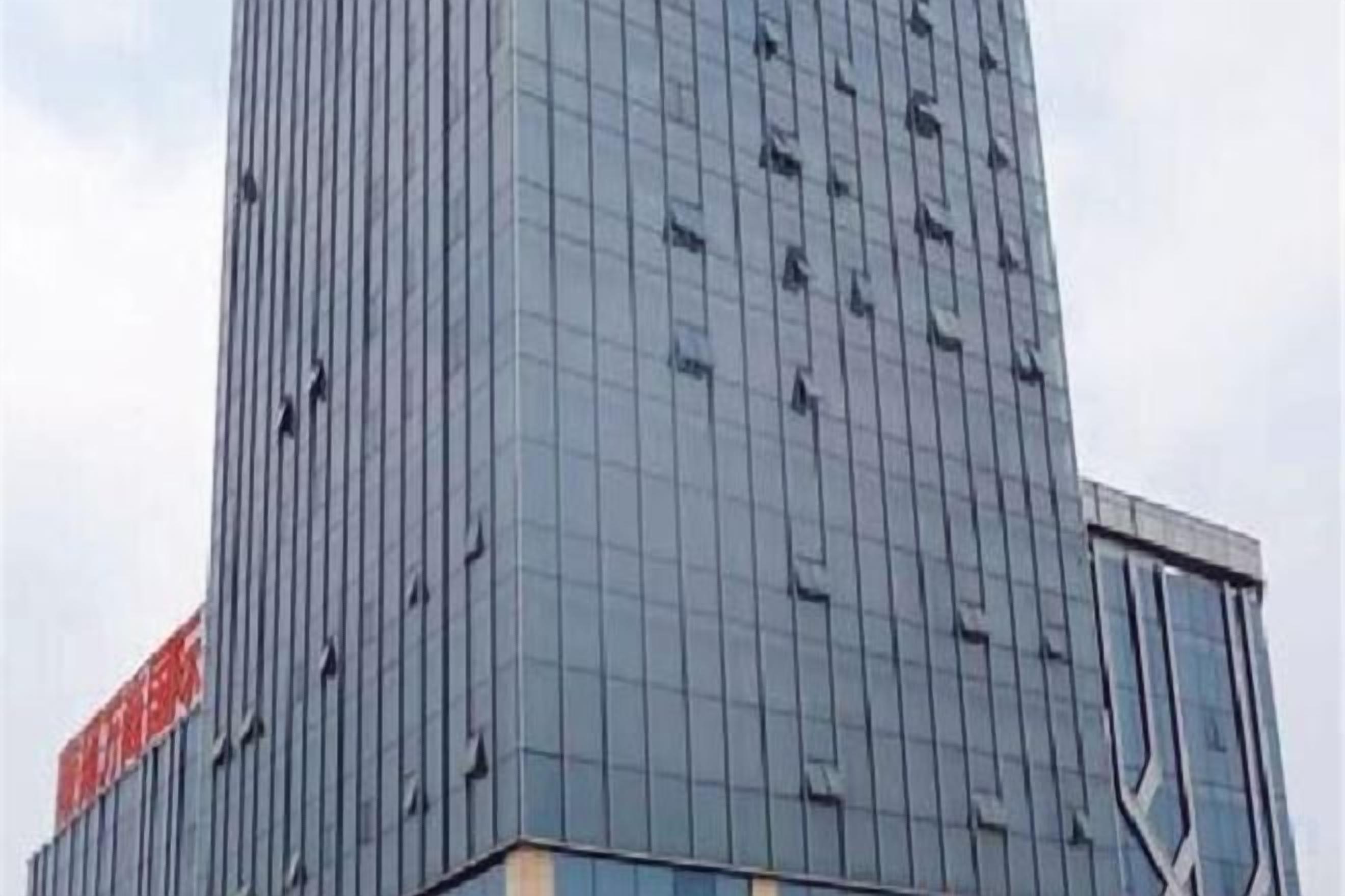 Un edificio alto y moderno con fachada de entramado y una entrada destacada en la base.