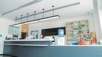 Una mesa de recepción con una pantalla digital, un dispensador de agua y una planta en maceta.