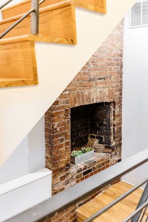Una escalera con una chimenea de ladrillo integrada en la pared, barandilla blanca y pasamanos de madera.