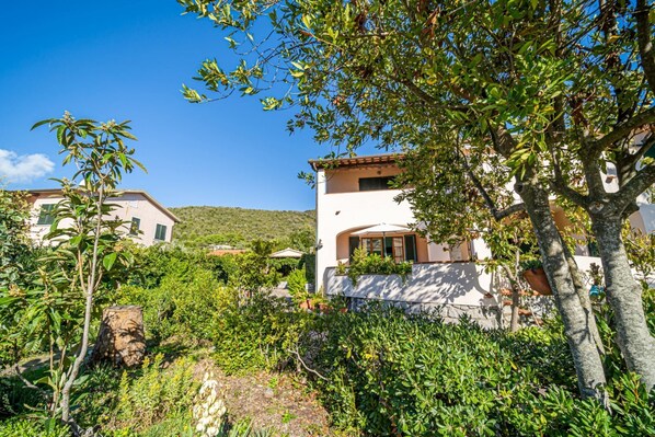 Eine Villa, umgeben von üppigem Grün, mit blauem Himmel.