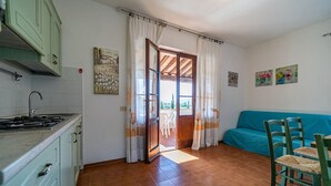 Een compacte keuken met een fornuis, kastjes en een eethoek met een tafel en stoelen.