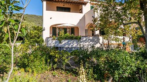 Een villa in mediterrane stijl met een witte gevel, boogvensters en een stenen muur.