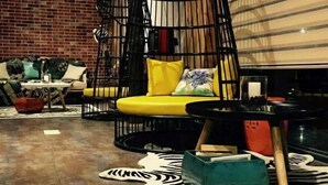 A cozy lounge area with a yellow sofa, a black metal chair, and a zebra-patterned rug. - Tuke China Hotel (Pingyang Aojiang Pearl Plaza Store) (Pingyang)