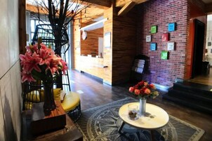 Un vestíbulo con pared de ladrillo, una escalera de caracol y una mesa redonda con flores.