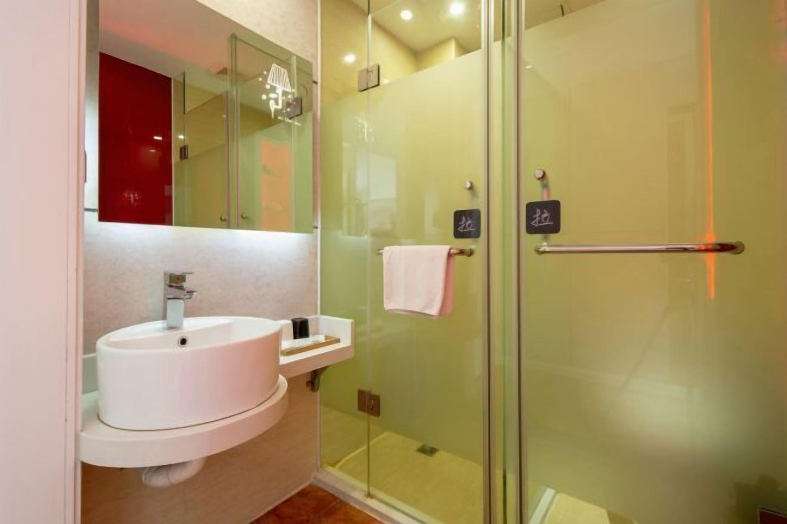 A modern bathroom with a white sink, glass shower enclosure, and a towel rack.