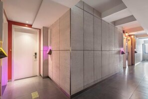 A modern hallway with a tiled floor, a door with a light switch, and a wall with a textured finish. - Tuke China Hotel (Pingyang Aojiang Pearl Plaza Store) (Pingyang)