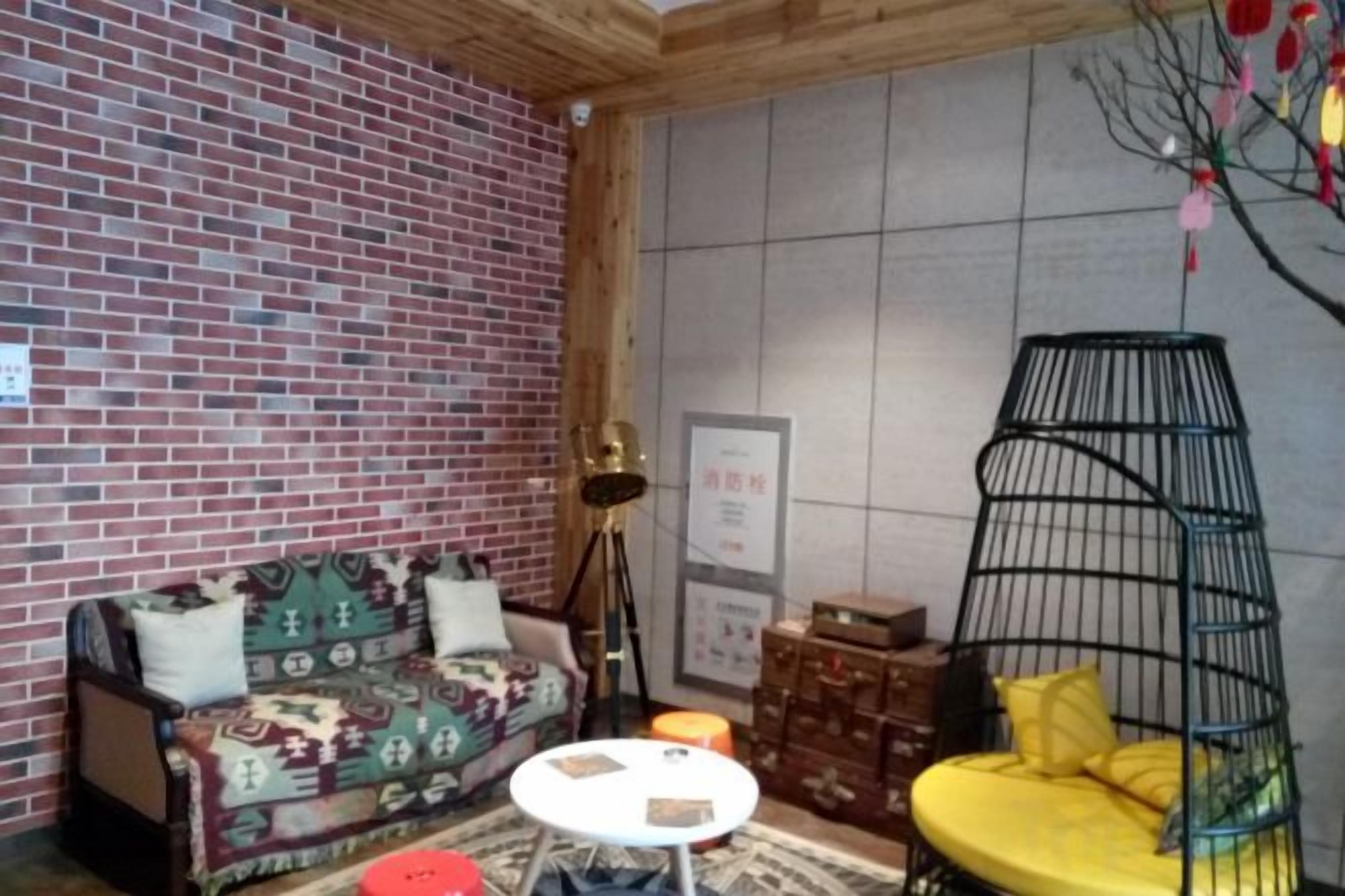 A room with a brick wall, a sofa, a hanging chair, and a small table.
