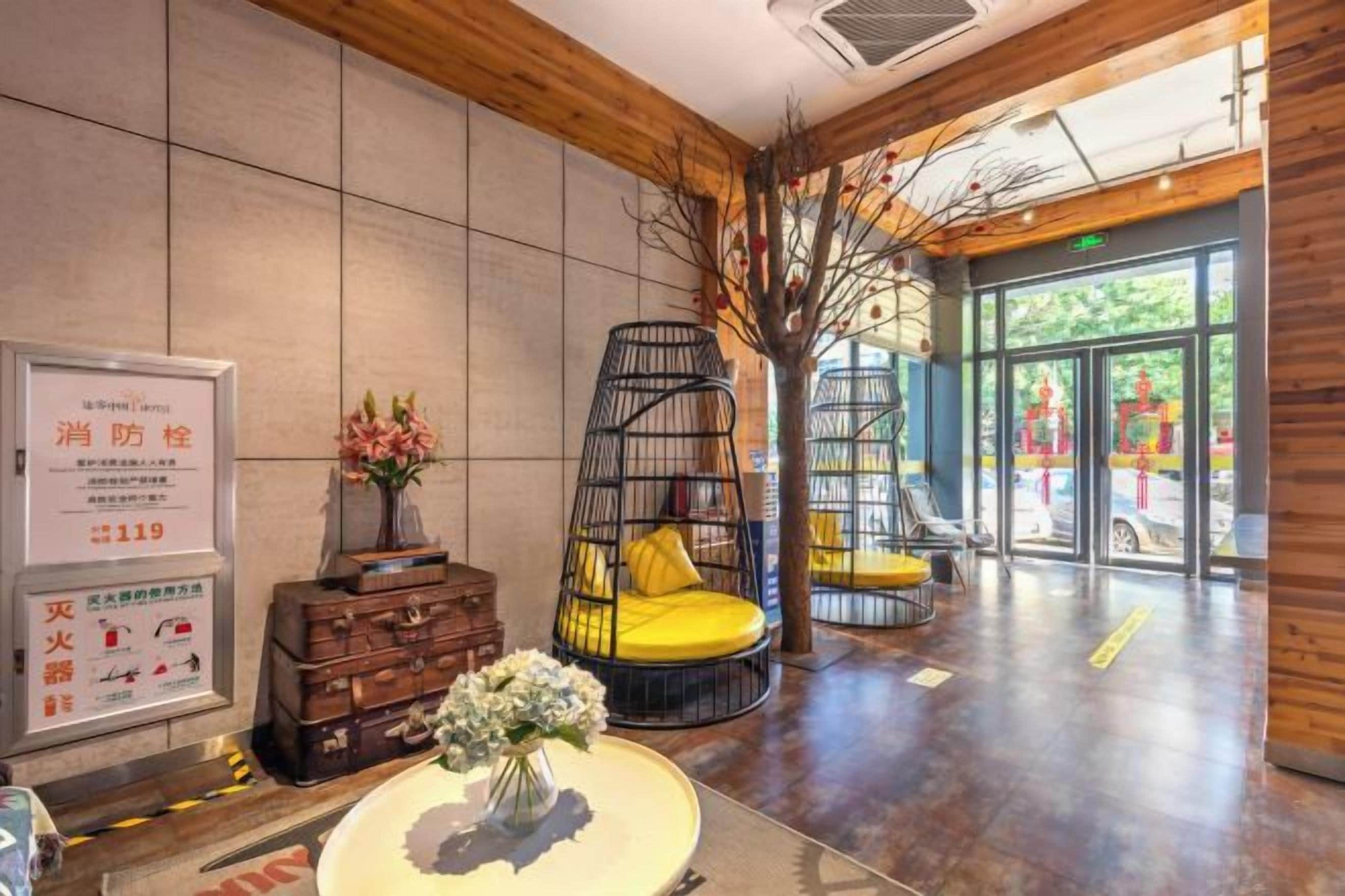 Eine Lobby mit einer Rezeption, einer Sitzecke mit einem gelben Sessel und einer Treppe zu einer oberen Ebene.