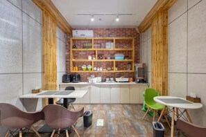 A compact kitchen with wooden shelves, a dining area with chairs, and a tiled floor. - Tuke China Hotel (Pingyang Aojiang Pearl Plaza Store) (Pingyang)