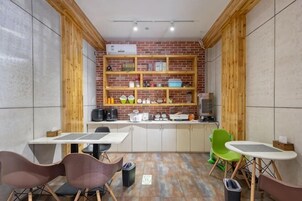 Una cocina compacta con estantes de madera, un comedor con sillas y suelo de baldosas.