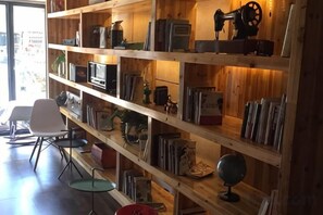 A room with wooden shelving containing various items, a white chair, and a small table. - Tuke China Hotel (Pingyang Aojiang Pearl Plaza Store) (Pingyang)