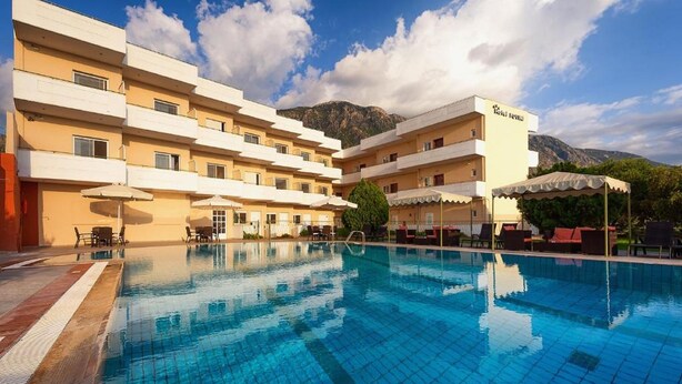 A hotel with a swimming pool, outdoor seating, and mountain views. - Hotel Fotini (Kalamata)