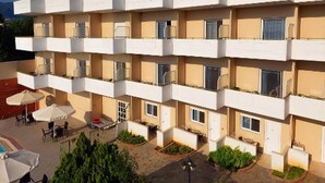 A multi-story hotel with balconies, outdoor seating, and a landscaped courtyard. - Hotel Fotini (Kalamata)