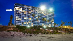 A multi-story hotel with a modern glass facade, located near a beach with palm trees. - WOW 10th Fl Corner Unit * Ocean Views * Pool + Hot Tub (San Diego)