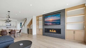 Un salon moderne avec une cheminée, un coin repas et un escalier.