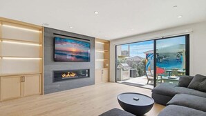 Un salon moderne avec une cheminée, un grand téléviseur et un balcon offrant une belle vue.