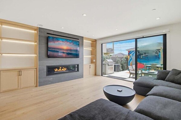 Una sala de estar moderna con chimenea, un televisor grande y un balcón con vistas.